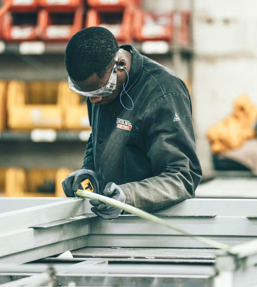 man using measuring tape in factory setting man using measuring tape in factory setting